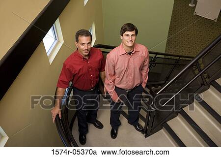 Stock Image - Portrait of two businessmen standing on a staircase. Fotosearch