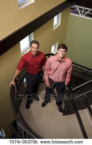 Stock Image - Portrait of two businessmen standing on a staircase. Fotosearch