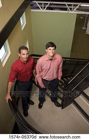 Stock Image - Portrait of two businessmen standing on a staircase. Fotosearch