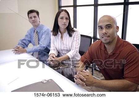 Stock Image - Portrait of two businesswomen and a businessman sitting in an office. Fotosearch