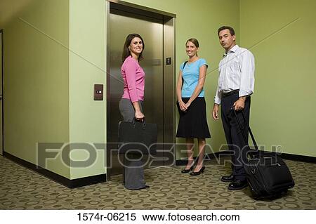 Portrait of two businesswomen and a businessman standing near an elevator View Large Photo Image Stock Photography - Portrait of two businesswomen and a businessman standing near an elevator. Fotosearch