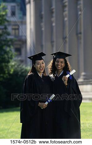 Stock Image - Portrait of two female graduates holding diplomas. Fotosearch