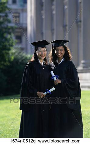 Stock Image - Portrait of two female graduates holding diplomas. Fotosearch