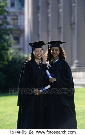 Stock Image - Portrait of two female graduates holding diplomas. Fotosearch
