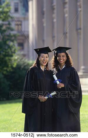 Stock Image - Portrait of two female graduates holding diplomas. Fotosearch