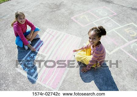 Portrait of two girls drawing on the ground with chalk View Large Photo Image Stock Image - Portrait of two girls drawing on the ground with chalk. Fotosearch