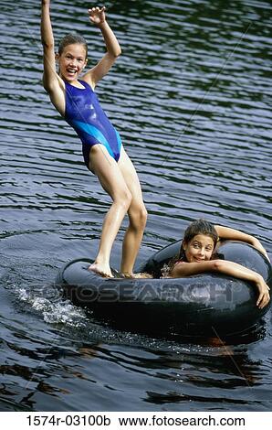 Stock Image - Portrait of two girls playing in water with inner tube. Fotosearch