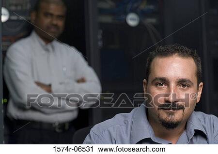 Stock Image - Portrait of two technicians in a server room. Fotosearch