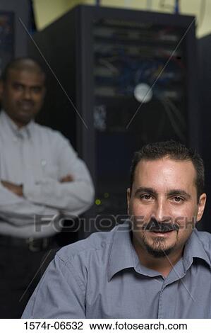 Stock Image - Portrait of two technicians in a server room. Fotosearch