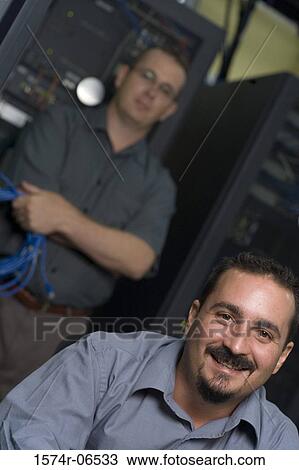 Stock Image - Portrait of two technicians in a server room. Fotosearch
