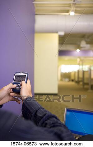 Rear view of a businessman holding a hand held device View Large Photo Image Stock Image - Rear view of a businessman holding a hand held device. Fotosearch