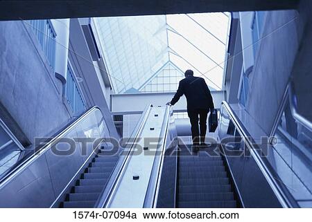 Rear view of a businessman on an escalator View Large Photo Image Stock Image - Rear view of a businessman on an escalator. Fotosearch