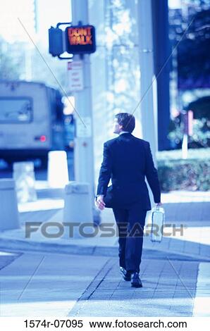 Rear view of a businessman walking on the street View Large Photo Image Stock Photography - Rear view of a businessman walking on the street. Fotosearch