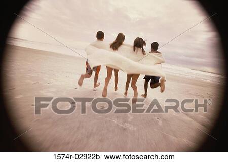 Stock Image - Rear view of a group of children running on the beach. Fotosearch
