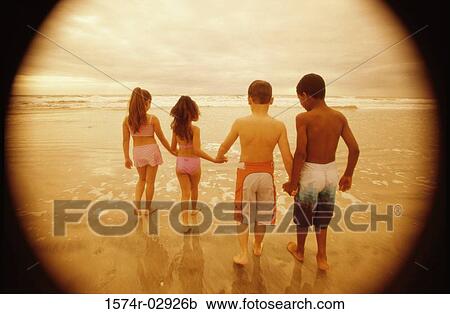 Stock Image - Rear view of a group of children walking on the beach. Fotosearch
