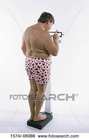 Stock Photograph - Rear view of a man standing on a scale. Fotosearch
