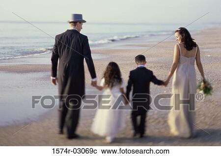 Rear view of a newlywed couple walking on the beach with a flower girl and a ring bearer View Large Photo Image Stock Image - Rear view of a newlywed couple walking on the beach with a flower girl and a ring bearer. Fotosearch