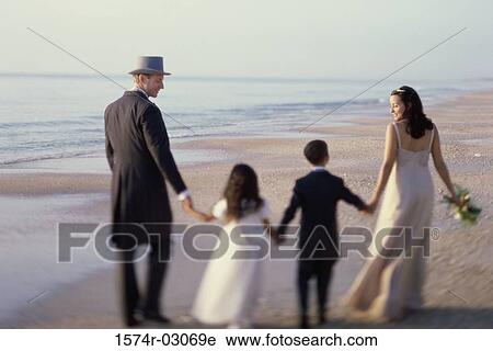 Rear view of a newlywed couple walking on the beach with a flower girl and a ring bearer View Large Photo Image Stock Image - Rear view of a newlywed couple walking on the beach with a flower girl and a ring bearer. Fotosearch