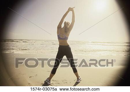 Rear view of a young woman exercising on the beach View Large Photo Image Stock Image - Rear view of a young woman exercising on the beach. Fotosearch