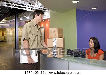 Stock Image - Receptionist receiving a package from a delivery man. Fotosearch
