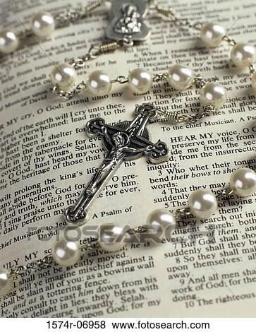 Rosary beads lying on an open Bible View Large Photo Image Stock Photo - Rosary beads lying on an open Bible. Fotosearch