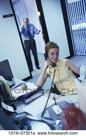 Secretary talking on a telephone with a businessman standing in a doorway behind View Large Photo Image Stock Image - Secretary talking on a telephone with a businessman standing in a doorway behind. Fotosearch