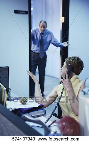 Secretary talking on a telephone with a businessman standing in a doorway behind View Large Photo Image Stock Photo - Secretary talking on a telephone with a businessman standing in a doorway behind. Fotosearch