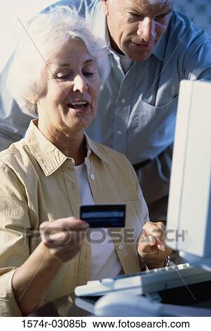 Senior couple in front of a computer holding a credit card View Large Photo Image Stock Image - Senior couple in front of a computer holding a credit card. Fotosearch