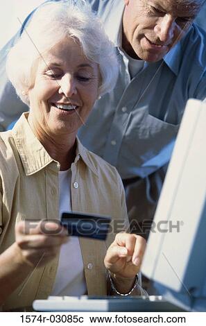 Senior couple in front of a computer holding a credit card View Large Photo Image Stock Image - Senior couple in front of a computer holding a credit card. Fotosearch