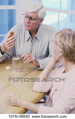 Stock Image - Senior couple looking at a pill bottle. Fotosearch