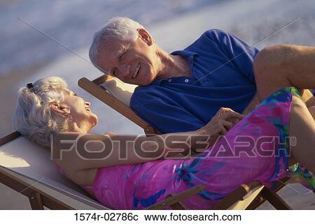 Stock Image - Senior couple sitting in deck chairs on the beach. Fotosearch