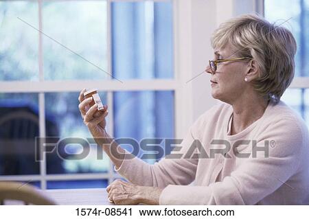Senior woman reading the label on a pill bottle View Large Photo Image Stock Image - Senior woman reading the label on a pill bottle. Fotosearch