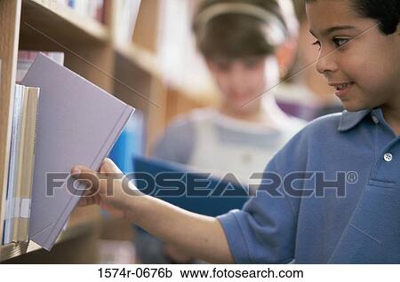 Side profile of a boy taking a book from a shelf in a library View Large Photo Image Stock Image - Side profile of a boy taking a book from a shelf in a library. Fotosearch