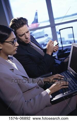Side profile of a businessman and a businesswoman sitting at an airport lounge View Large Photo Image Stock Image - Side profile of a businessman and a businesswoman sitting at an airport lounge. Fotosearch
