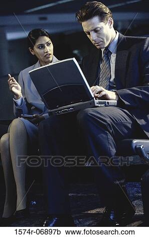 Side profile of a businessman and businesswoman sitting in front of a laptop View Large Photo Image Stock Image - Side profile of a businessman and businesswoman sitting in front of a laptop. Fotosearch