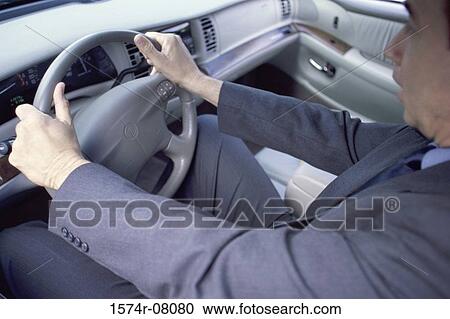 Stock Image - Side profile of a businessman driving a car. Fotosearch