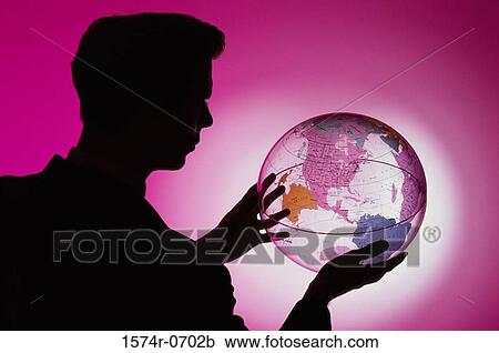 Stock Image - Side profile of a businessman holding a globe. Fotosearch