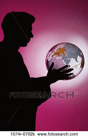 Stock Image - Side profile of a businessman holding a globe. Fotosearch