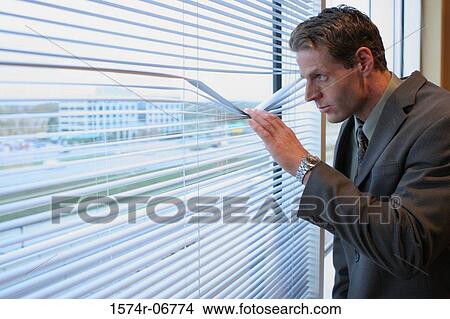 Picture - Side profile of a businessman looking through a window. Fotosearch