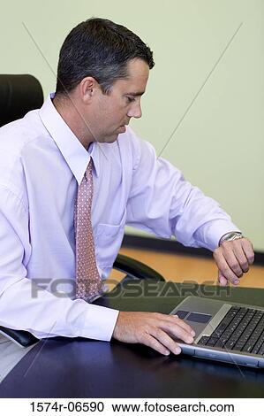 Side profile of a businessman looking at his wristwatch View Large Photo Image Stock Image - Side profile of a businessman looking at his wristwatch. Fotosearch