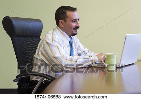 Stock Photo - Side profile of a businessman working on a laptop. Fotosearch