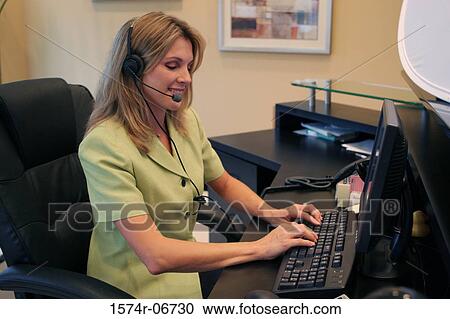 Side profile of a businesswoman wearing a headset working on a computer View Large Photo Image Stock Image - Side profile of a businesswoman wearing a headset working on a computer. Fotosearch