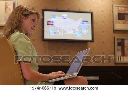Stock Image - Side profile of a businesswoman working on a laptop. Fotosearch