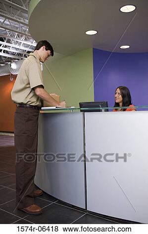 Side profile of a delivery man writing on a paper at a reception desk View Large Photo Image Stock Photo - Side profile of a delivery man writing on a paper at a reception desk. Fotosearch