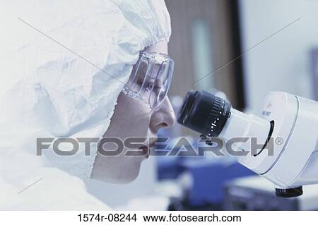 Picture - Side profile of a female researcher looking through a microscope. Fotosearch