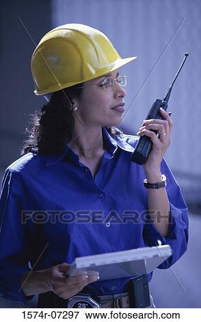Stock Photo - Side profile of a forewoman talking on a walkie-talkie. Fotosearch