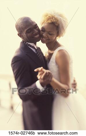 Stock Image - Side profile of a newlywed couple dancing. Fotosearch