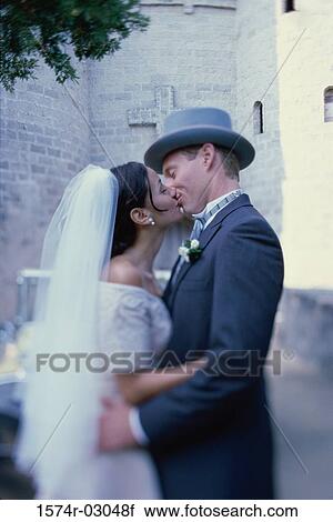 Stock Image - Side profile of a newlywed couple kissing each other. Fotosearch