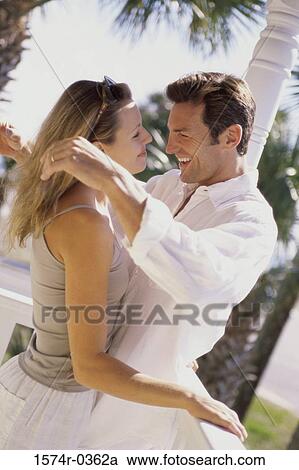Stock Image - Side profile of a young couple embracing. Fotosearch