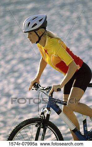 Side profile of a young woman cycling View Large Photo Image Stock Image - Side profile of a young woman cycling. Fotosearch